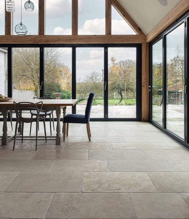 Open plan kitchen diner with vaulted ceilings and large glass windows looking out into the garden.