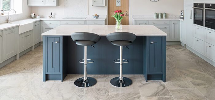 Cottage-style kitchen with contrasting colour cabinets and kitchen island. Featuring our limestone flooring.