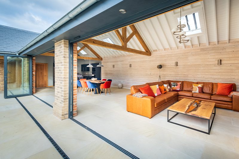 Stone extension overlooking the pool, featuring bright furniture and oak beams into the ceiling.