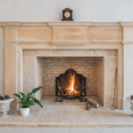 Natural stone fireplace against a white wall with a warm fire glowing inside.