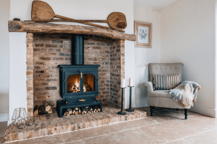 Brick fireplace surround with wood-burning fire and natural stone flooring